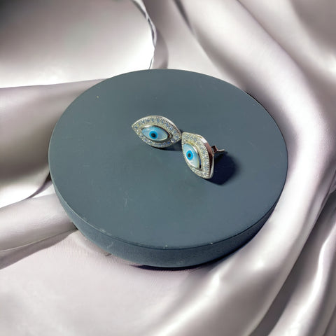 a pair of earrings sitting on top of a round box