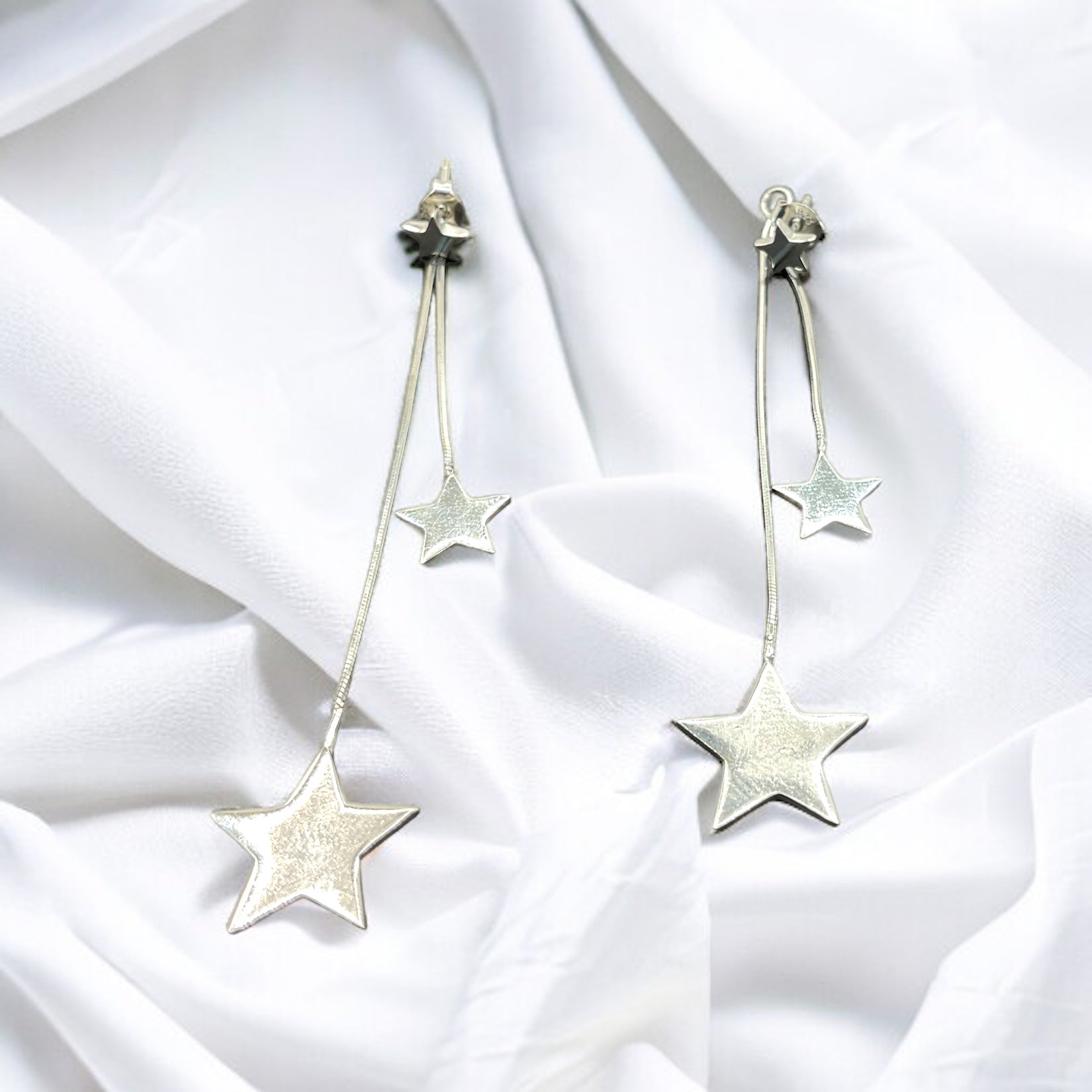 a pair of earrings with stars hanging from them