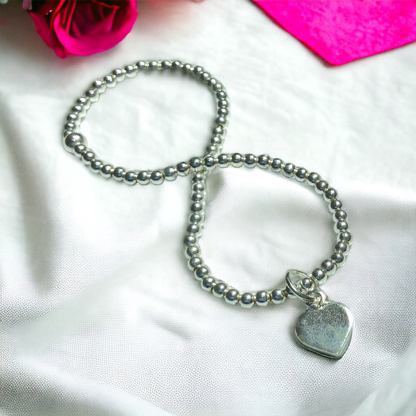 a silver beaded bracelet with a heart charm