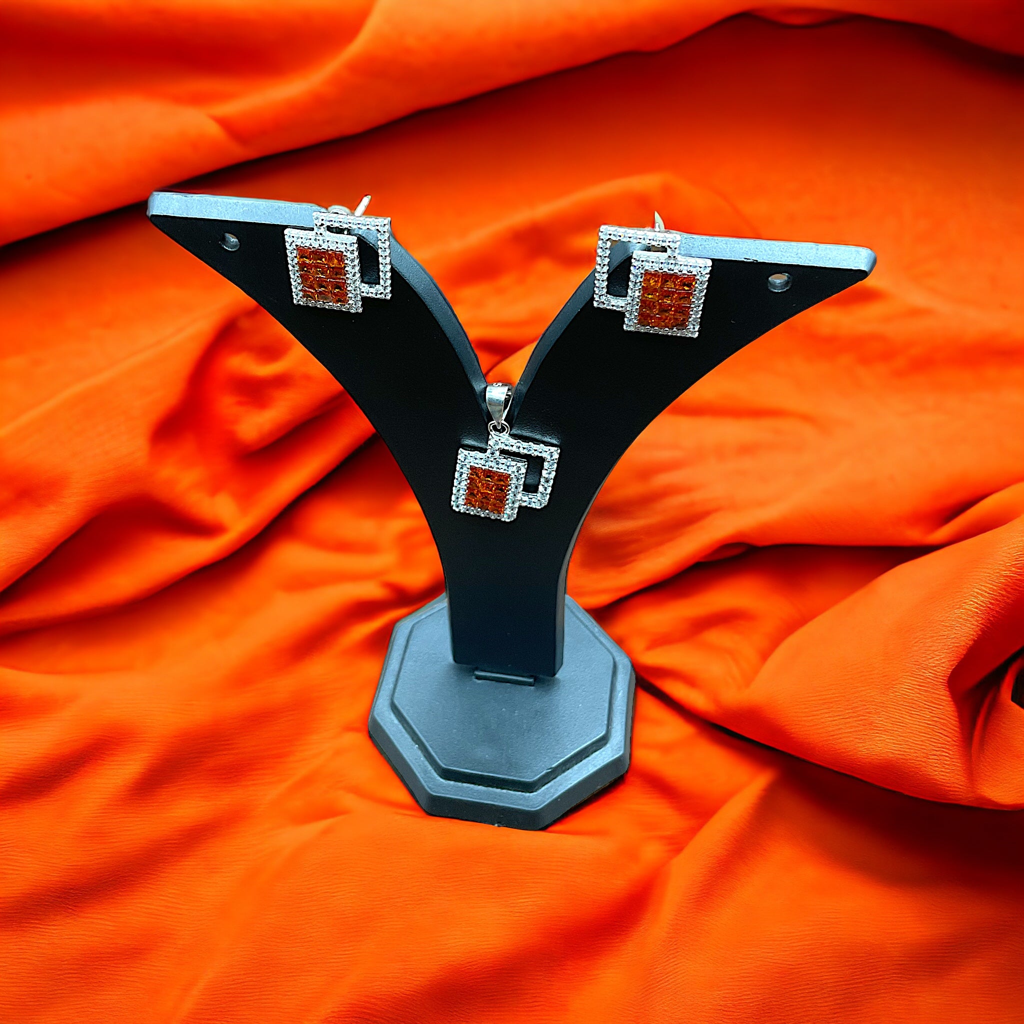 a pair of earrings sitting on top of an orange cloth