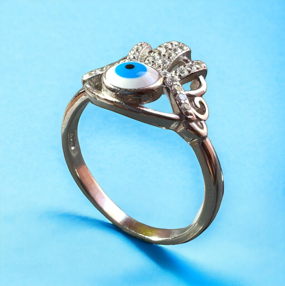 a silver ring with a blue eye and a flower