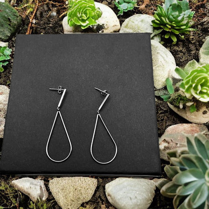 a pair of earrings sitting on top of a black box