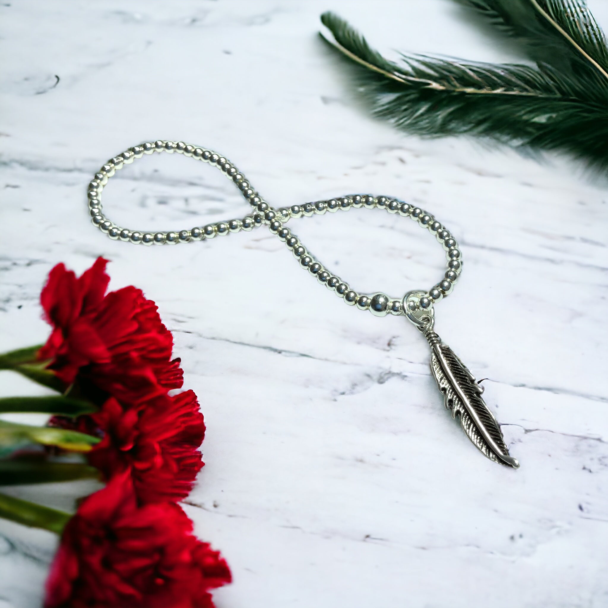 a necklace with a feather on a chain