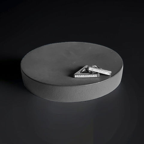 a pair of silver earrings sitting on top of a round box
