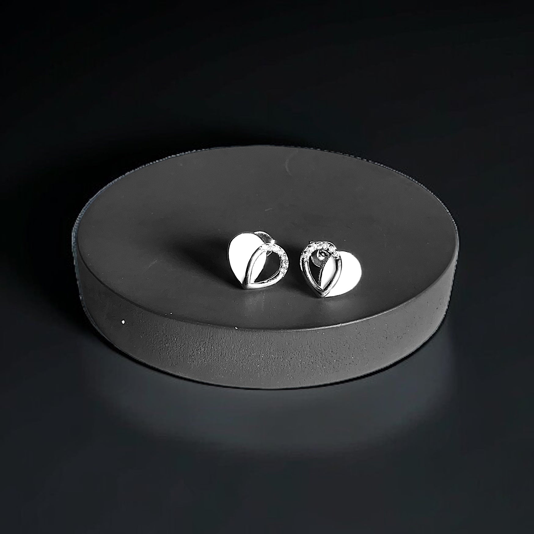 a pair of silver earrings sitting on top of a black surface