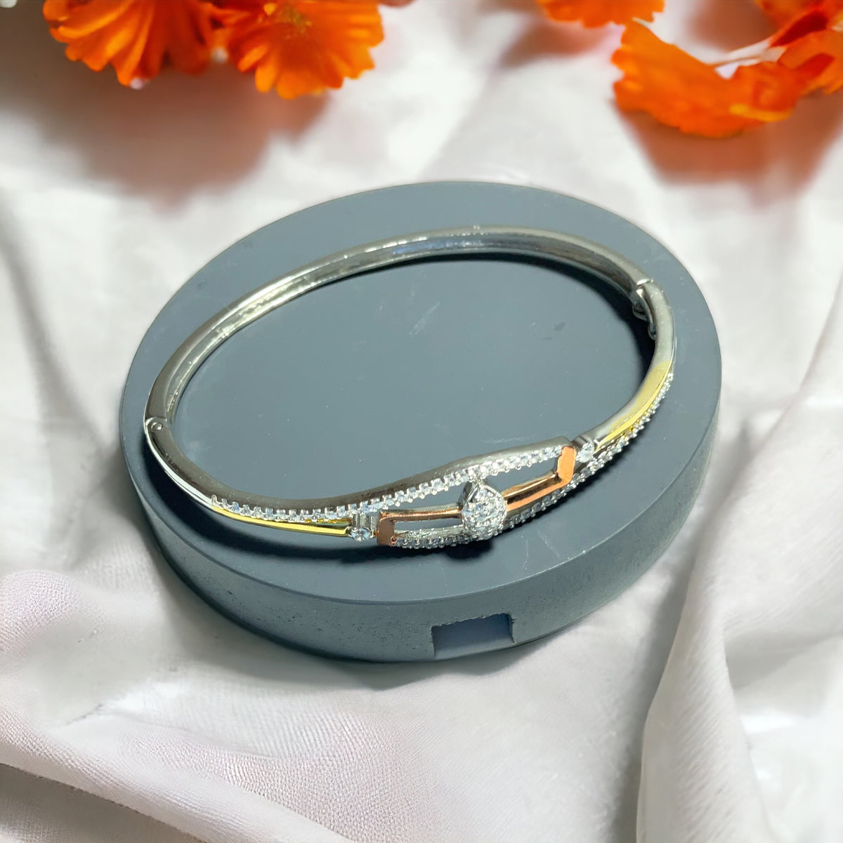 a silver and gold bracelet on a white cloth
