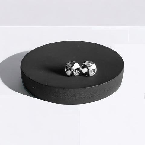 a pair of earrings sitting on top of a black stand