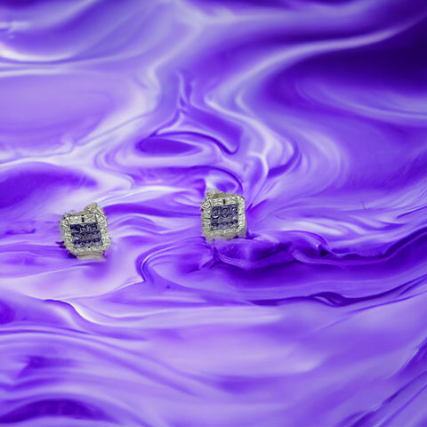 a pair of earrings sitting on top of a purple surface