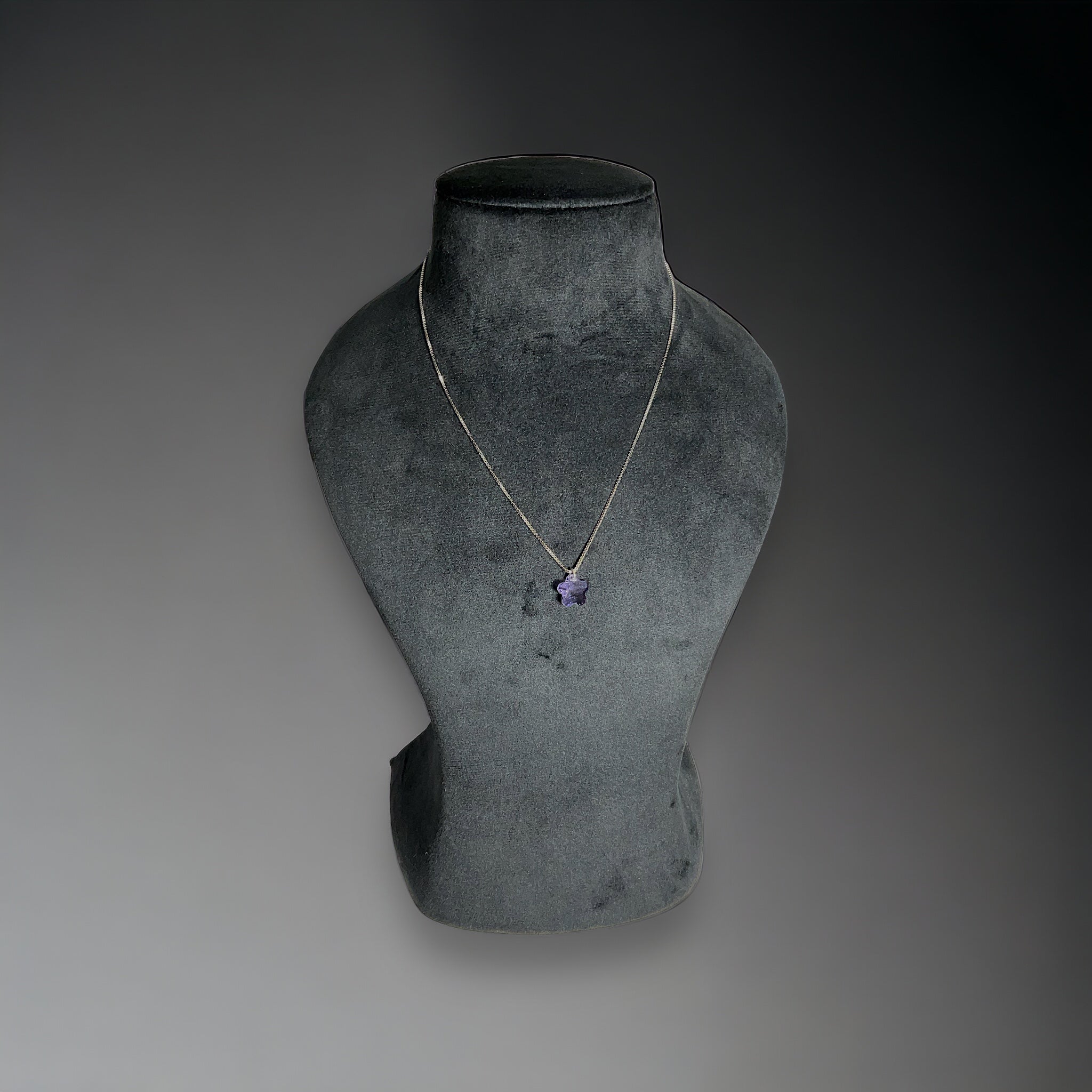 a necklace on a mannequin on a gray background