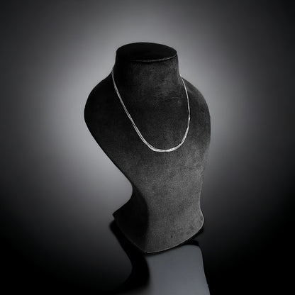 a black and white photo of a necklace on a mannequin