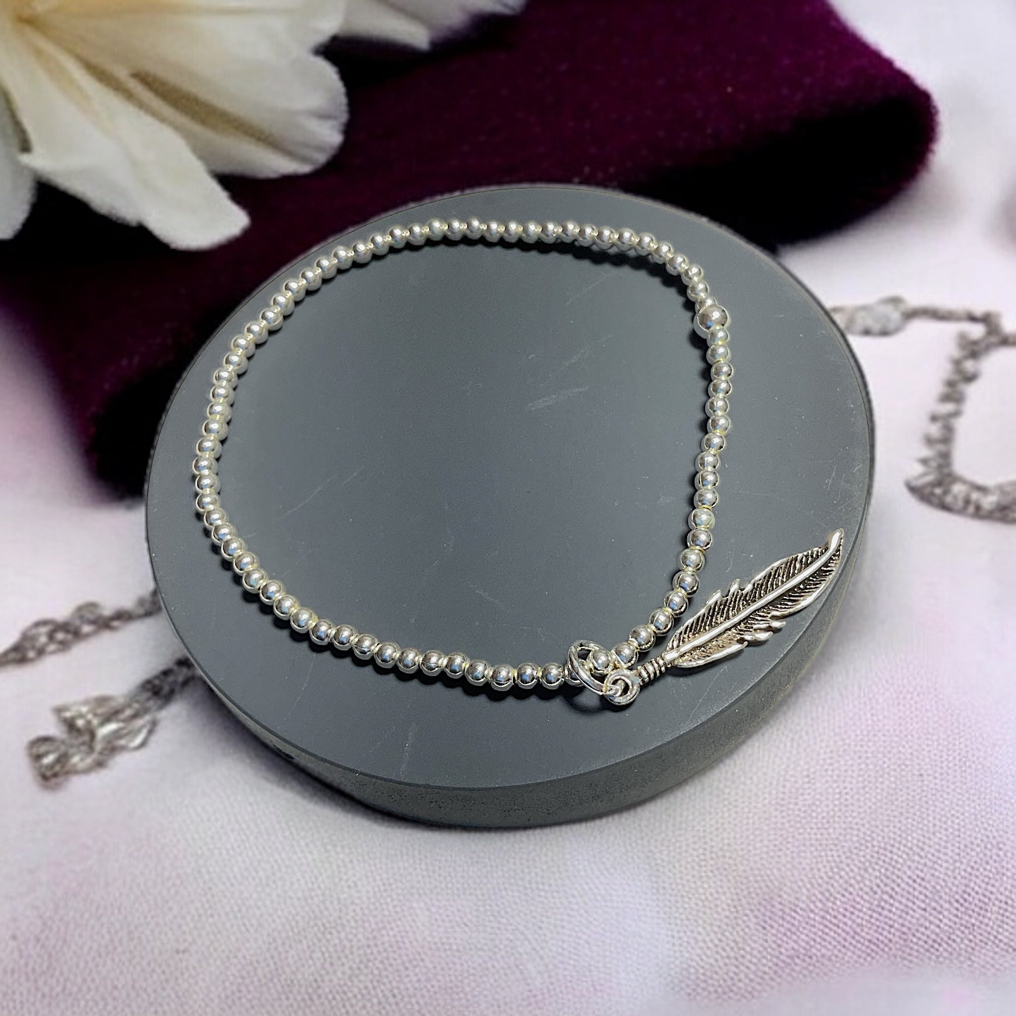 a necklace with a feather charm on it