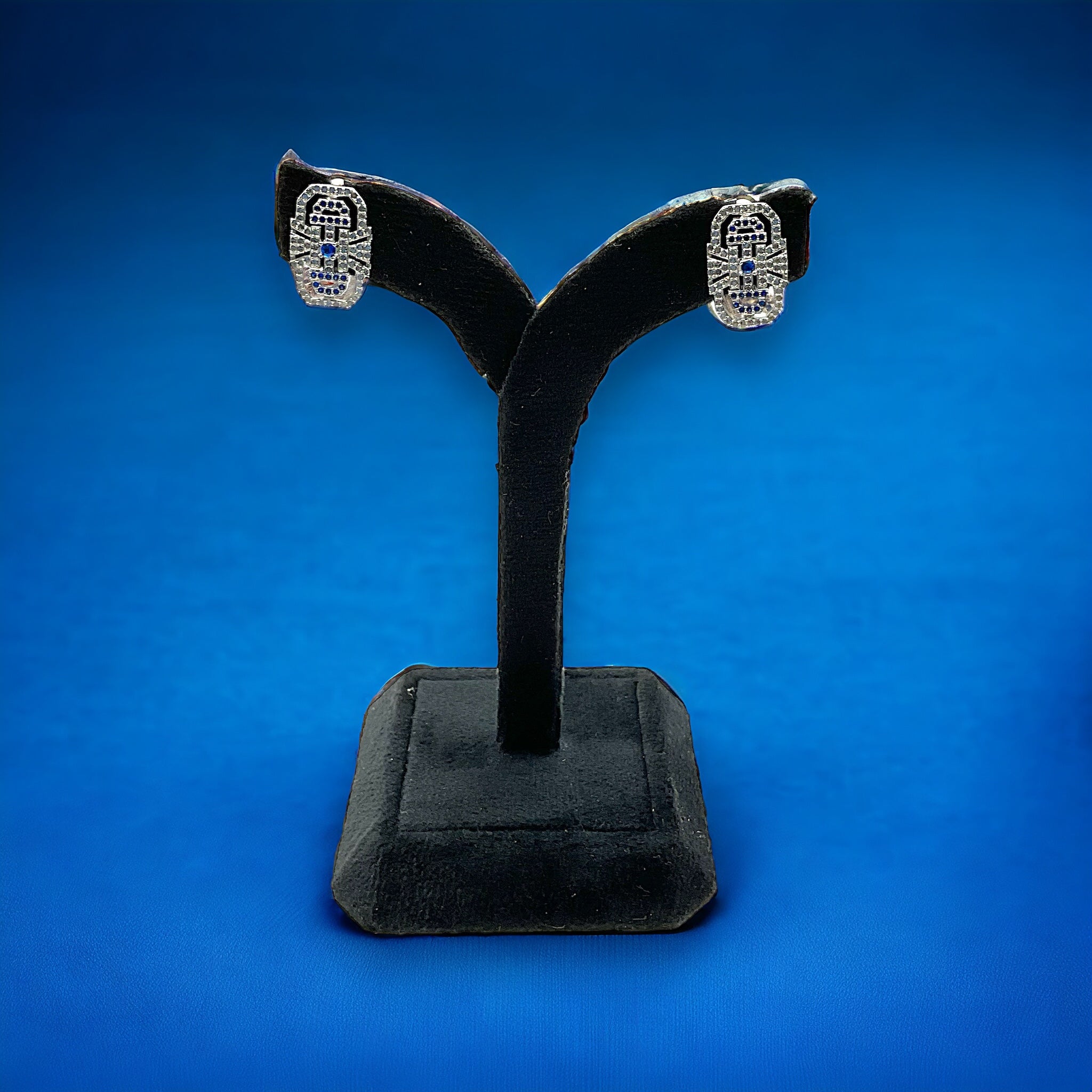 a pair of earrings on a stand on a blue background
