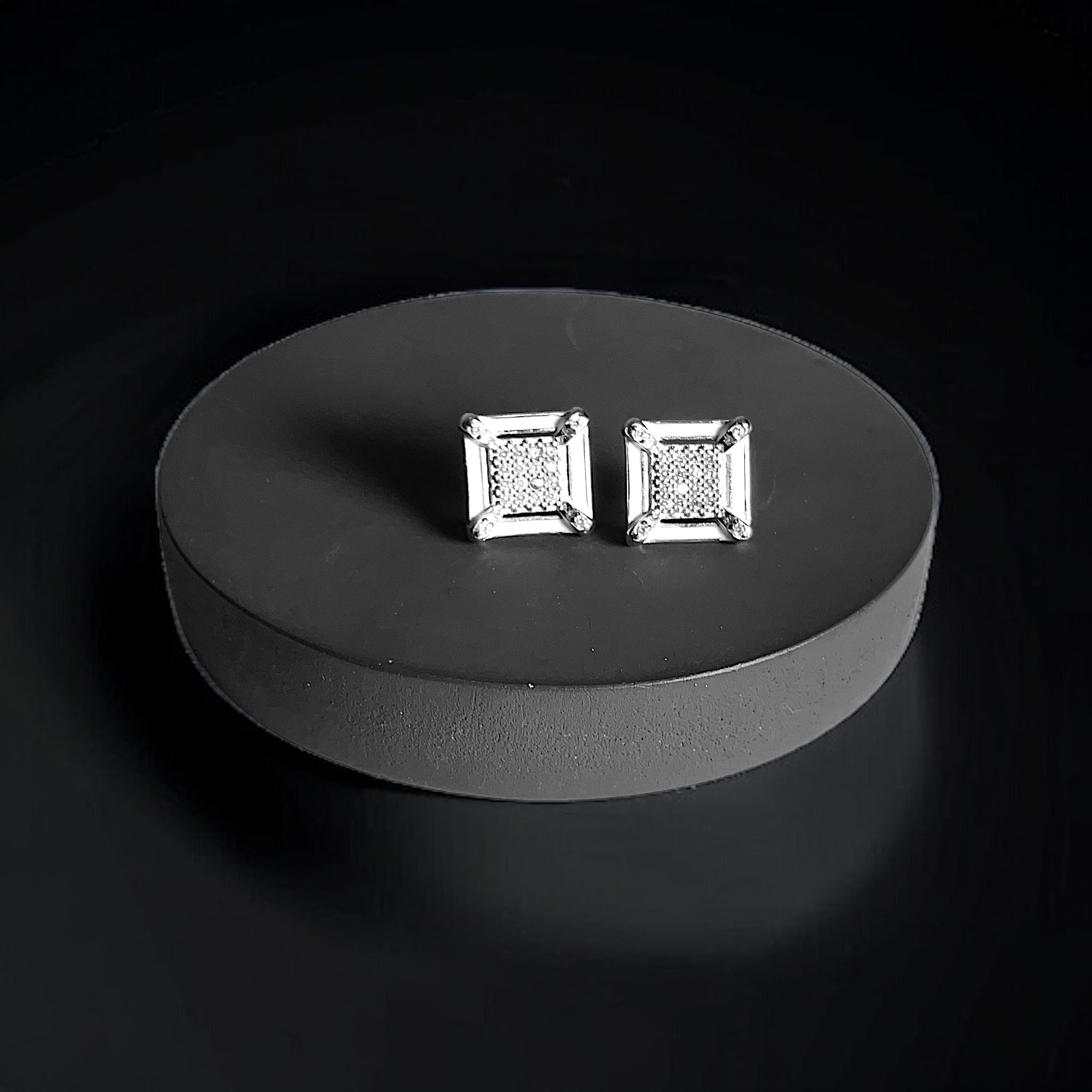 a pair of diamond earrings sitting on top of a black surface