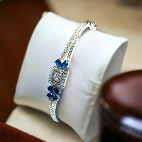 a blue and white bracelet sitting on top of a white pillow