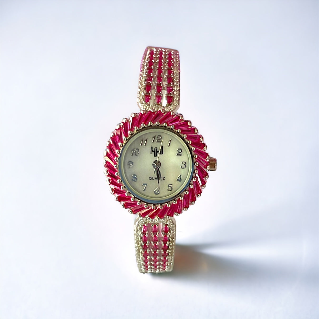 a red and gold watch sitting on a white surface