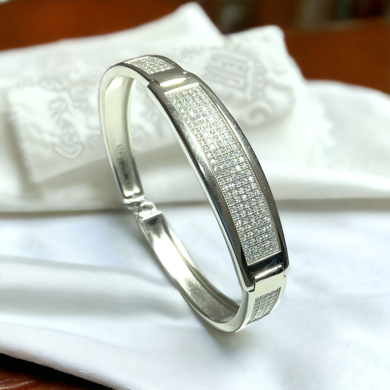 a close up of a silver bracelet on a white cloth
