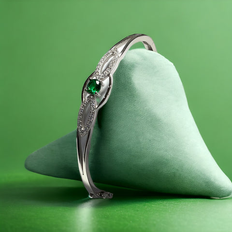 a ring with a green stone sits on a pillow