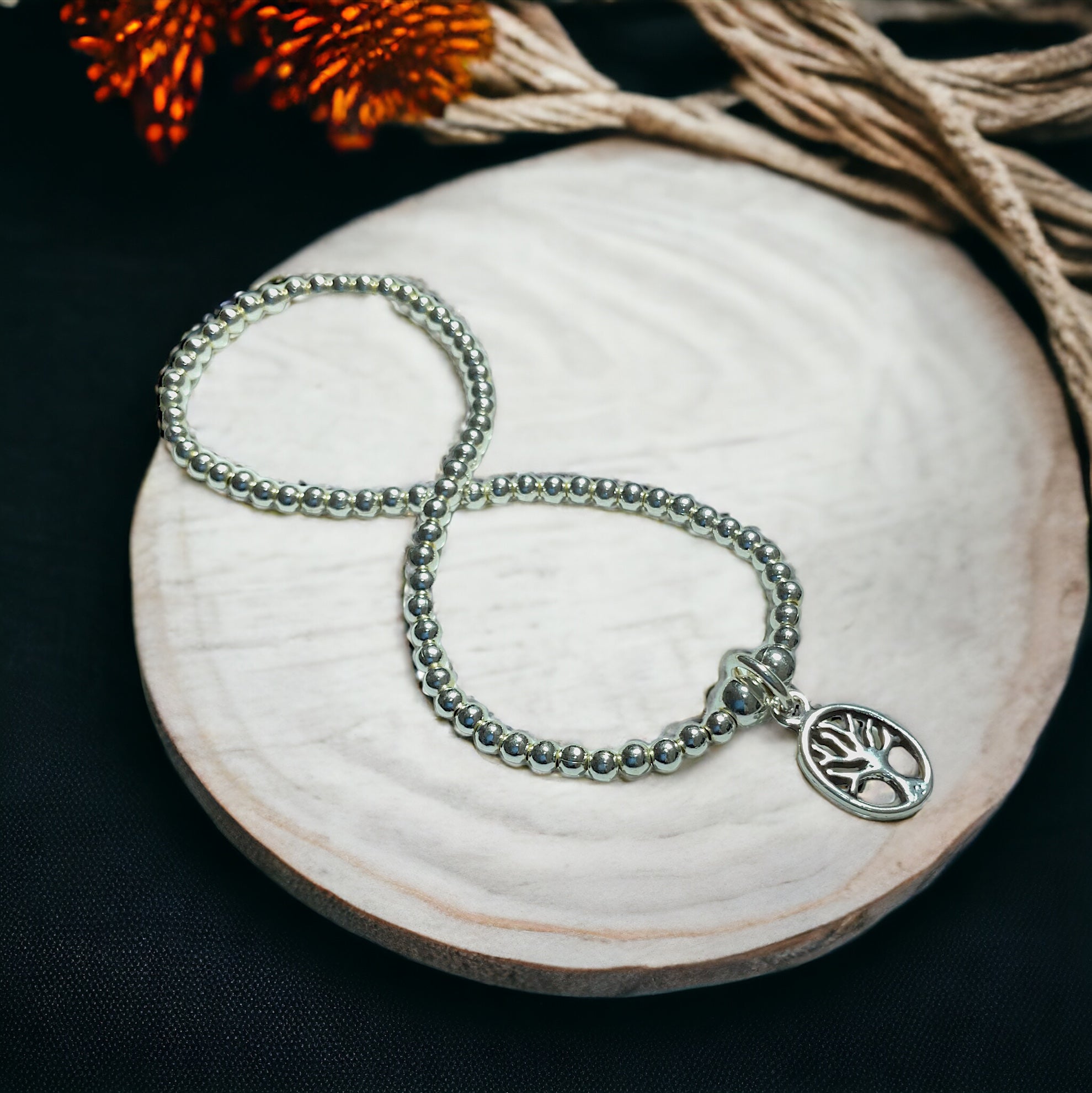 a beaded bracelet with a tree of life charm