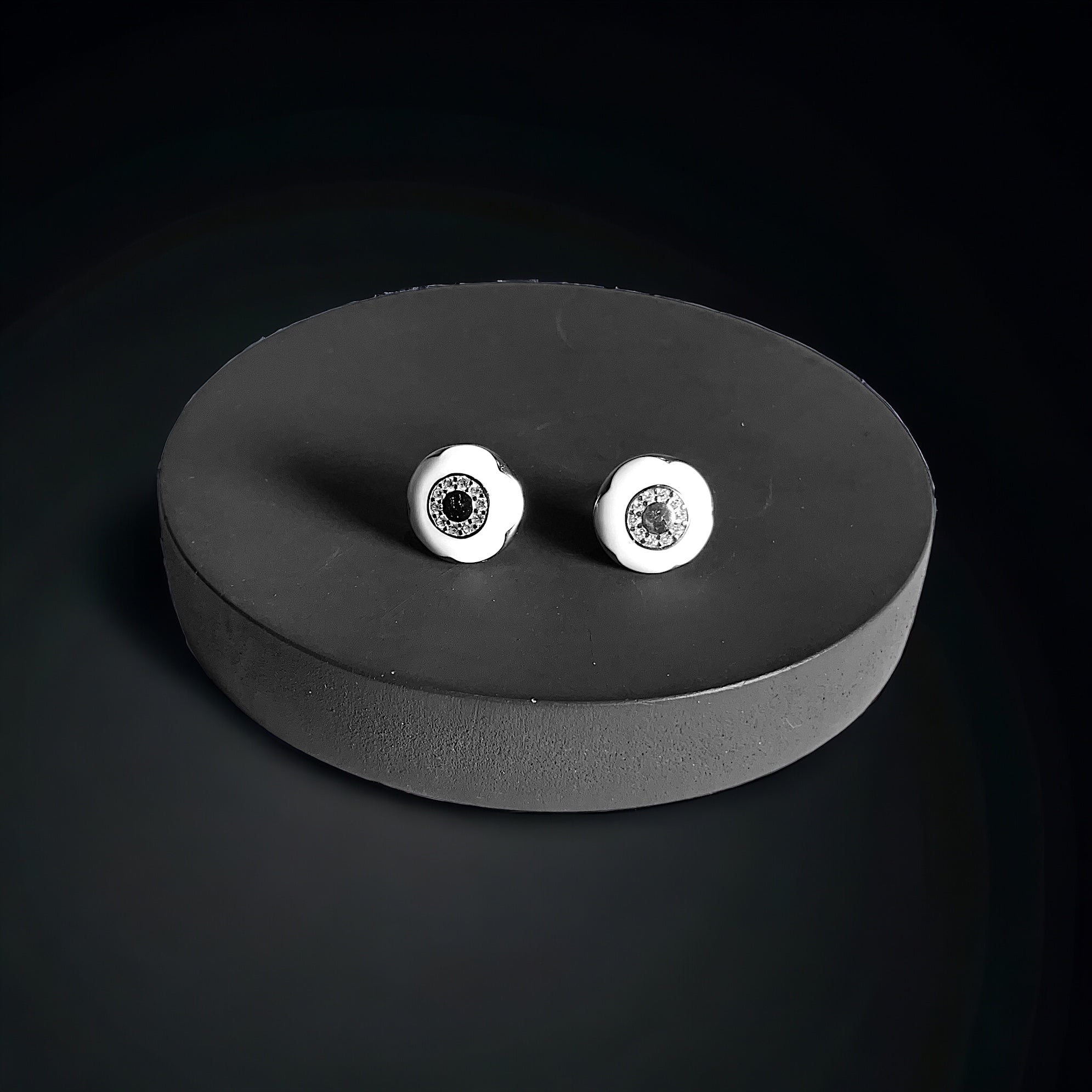 a pair of white diamond stud earrings on a black surface
