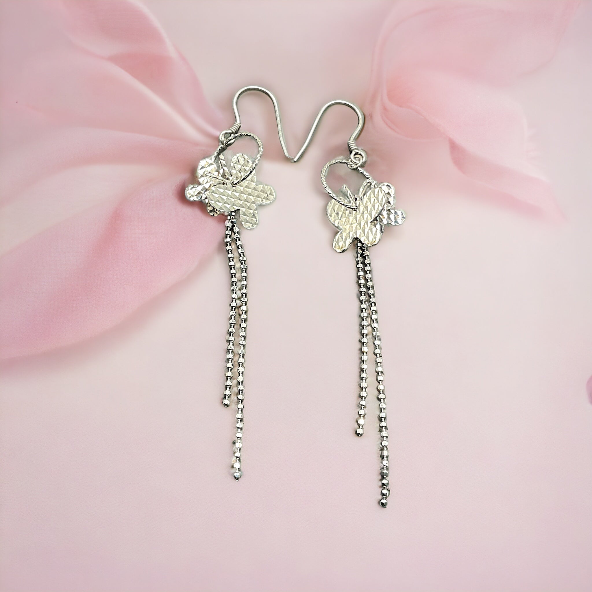 a pair of earrings with a flower and a chain hanging from it