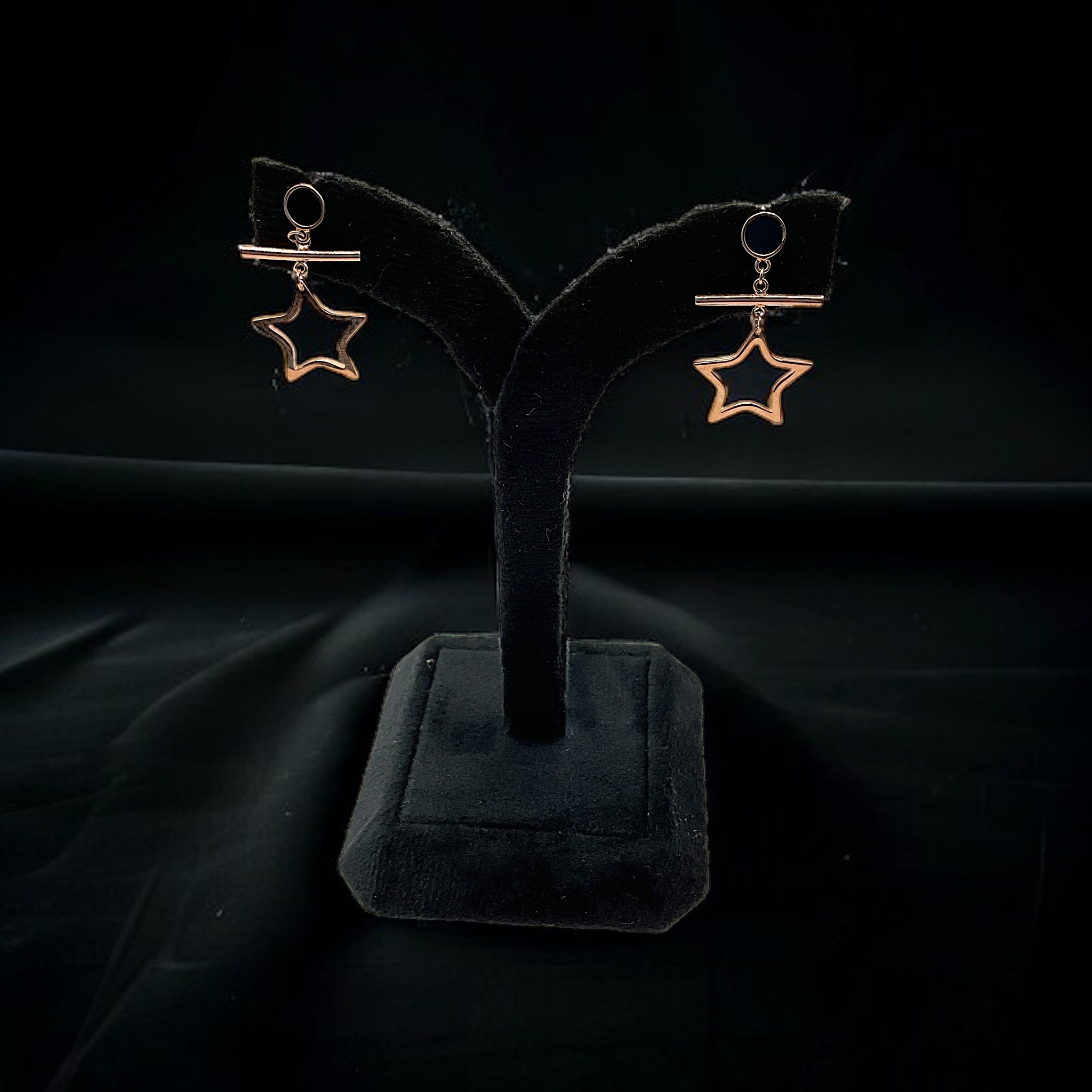 a pair of earrings on a stand on a black background