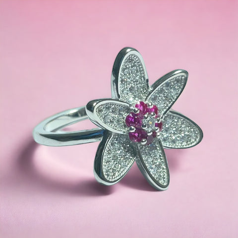a silver ring with a pink flower on a pink background