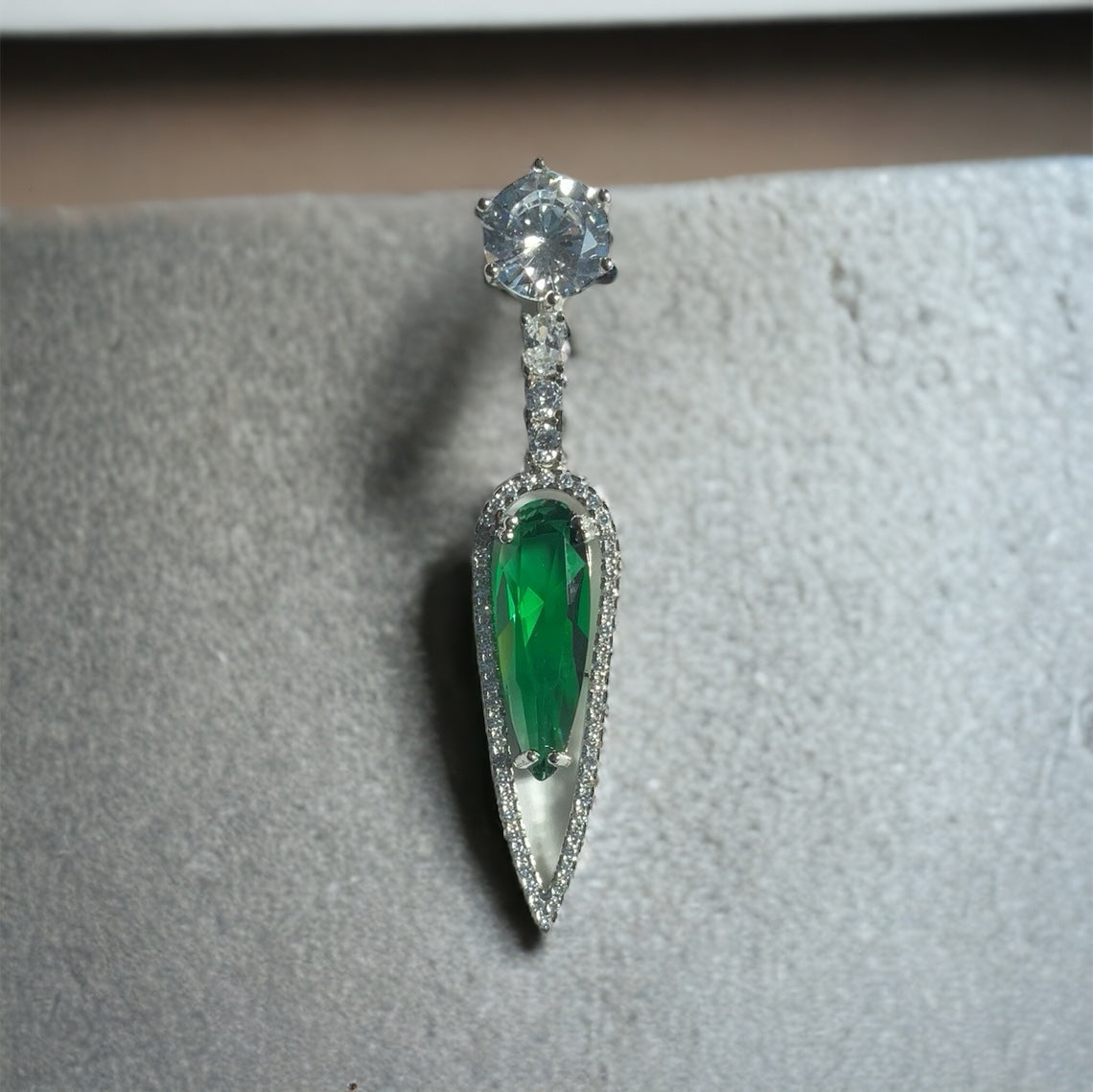 a close up of a brooch with a green stone