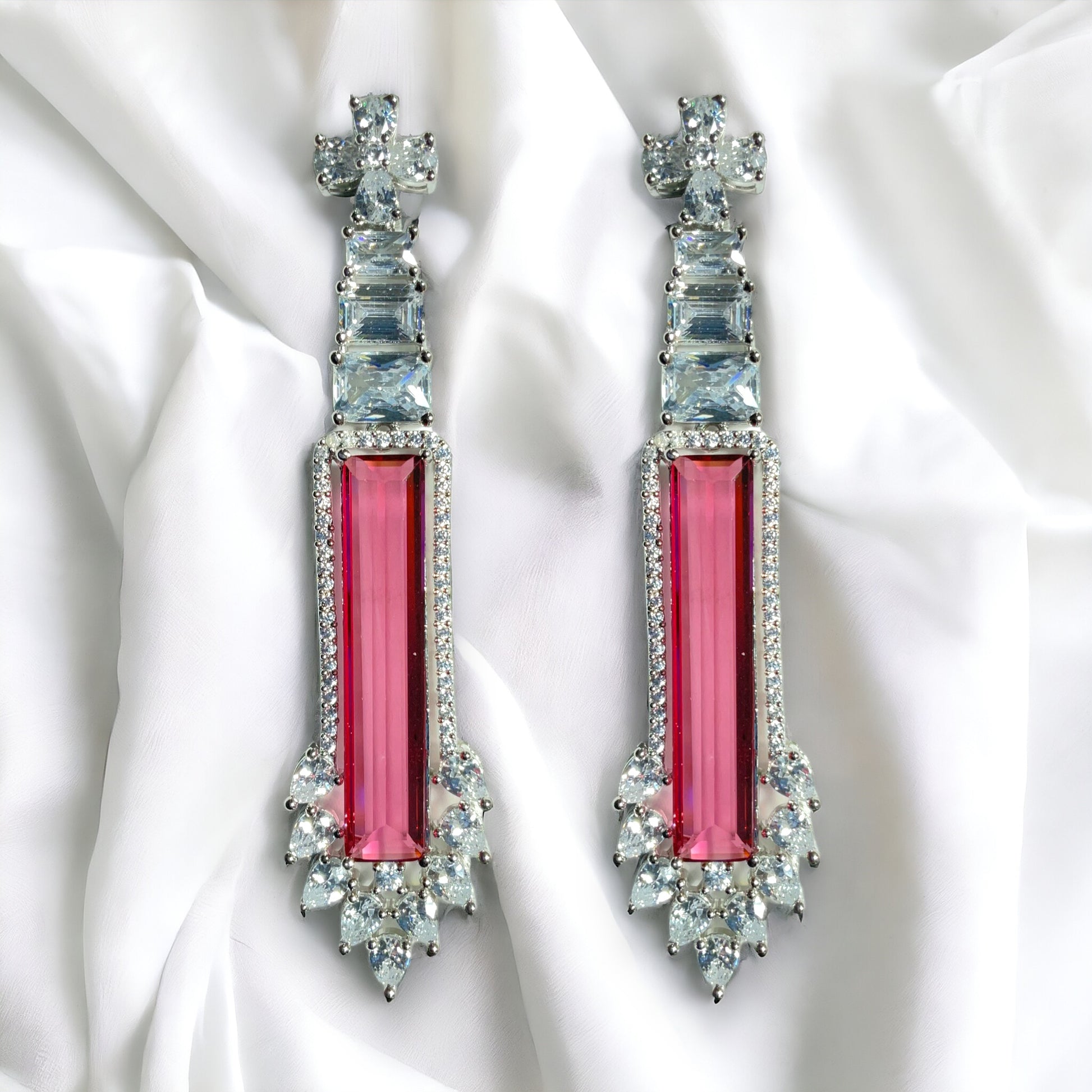 a pair of pink and white earrings on a white cloth