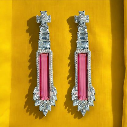 a pair of pink and clear earrings on a yellow background