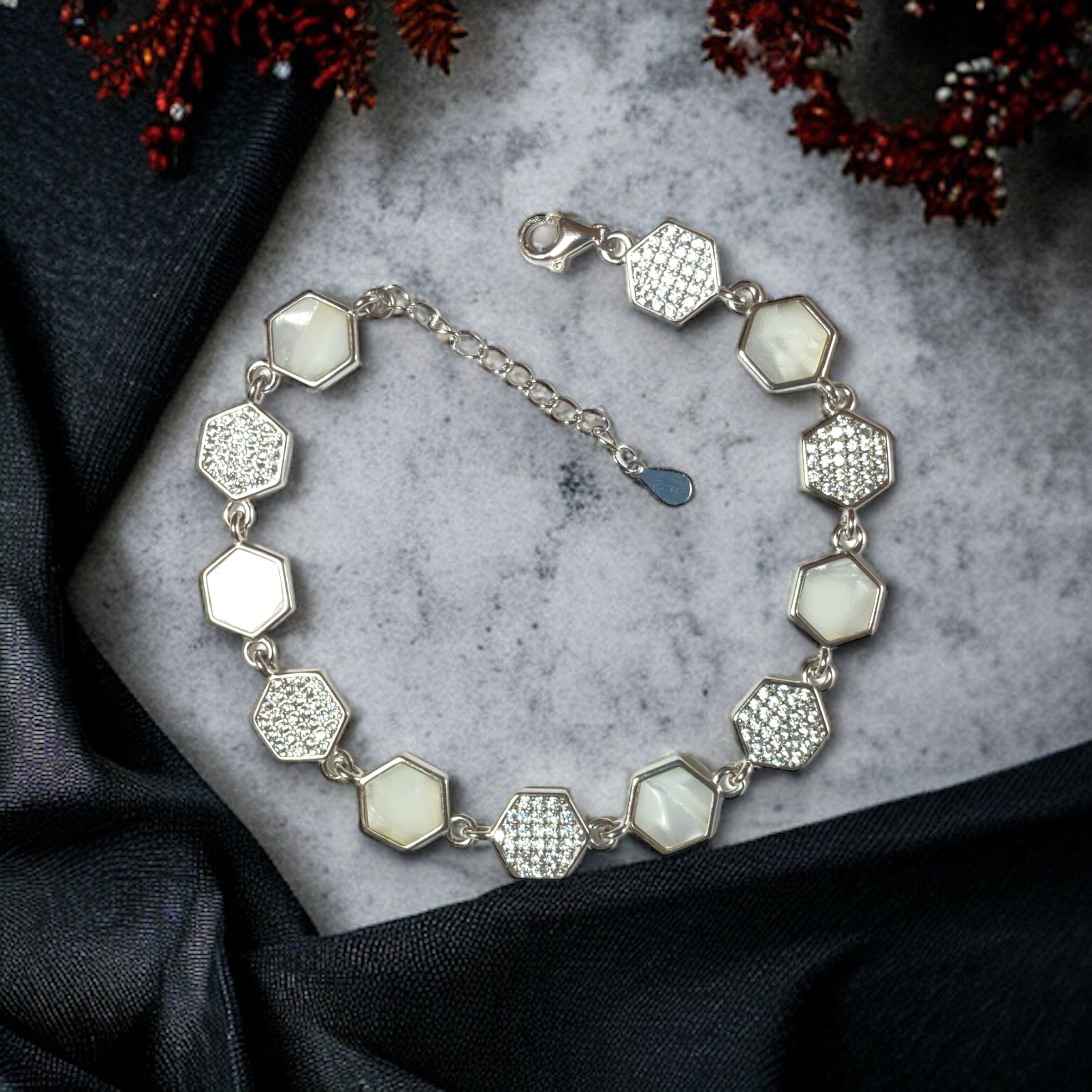 a silver bracelet with white stones on a marble surface