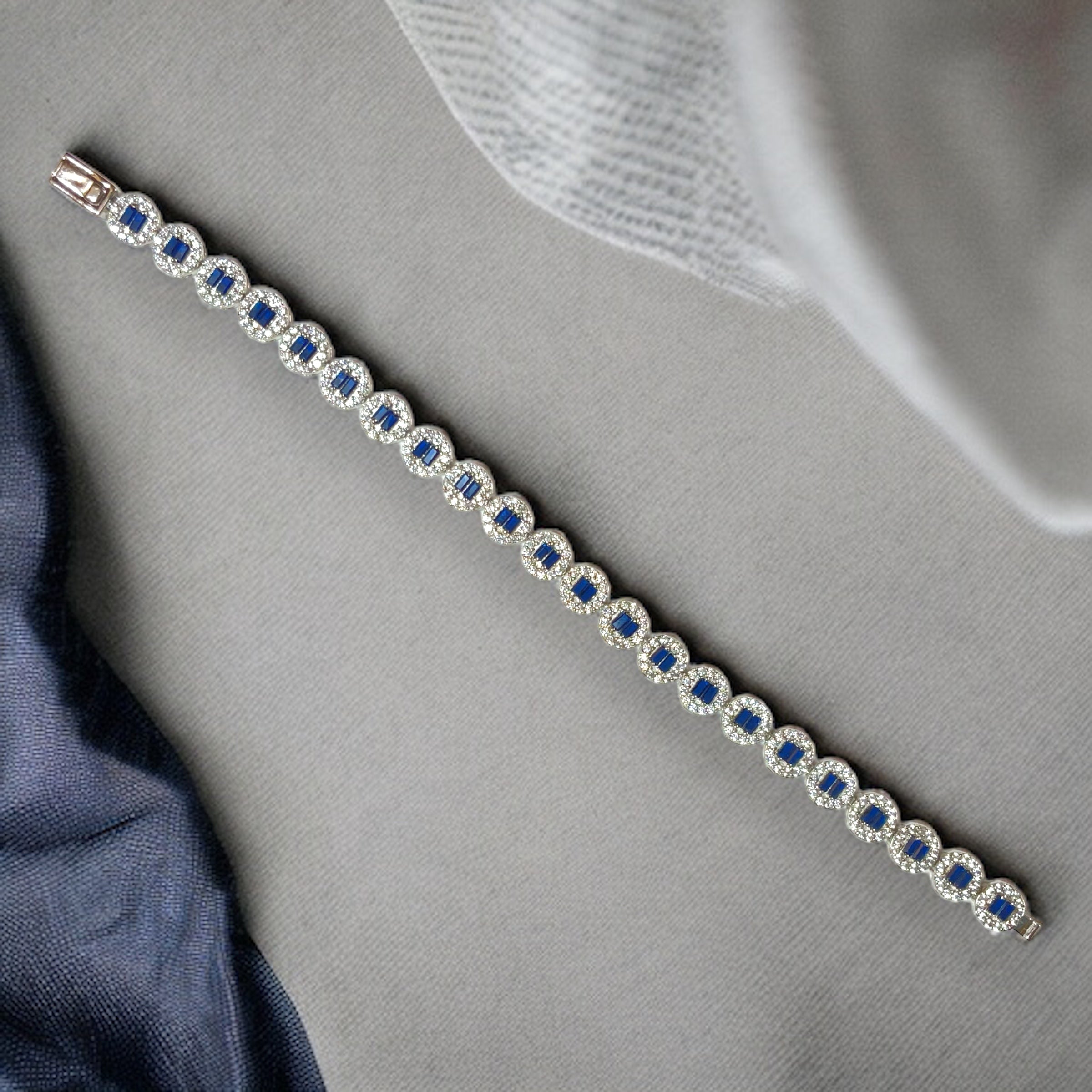 a diamond and sapphire bracelet on a blue cloth