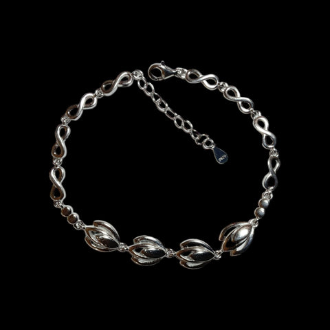 a silver chain bracelet with a clasp on a black background