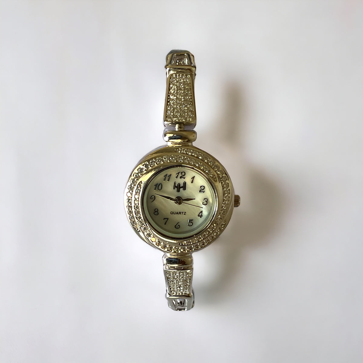 a gold watch with a white face on a white background