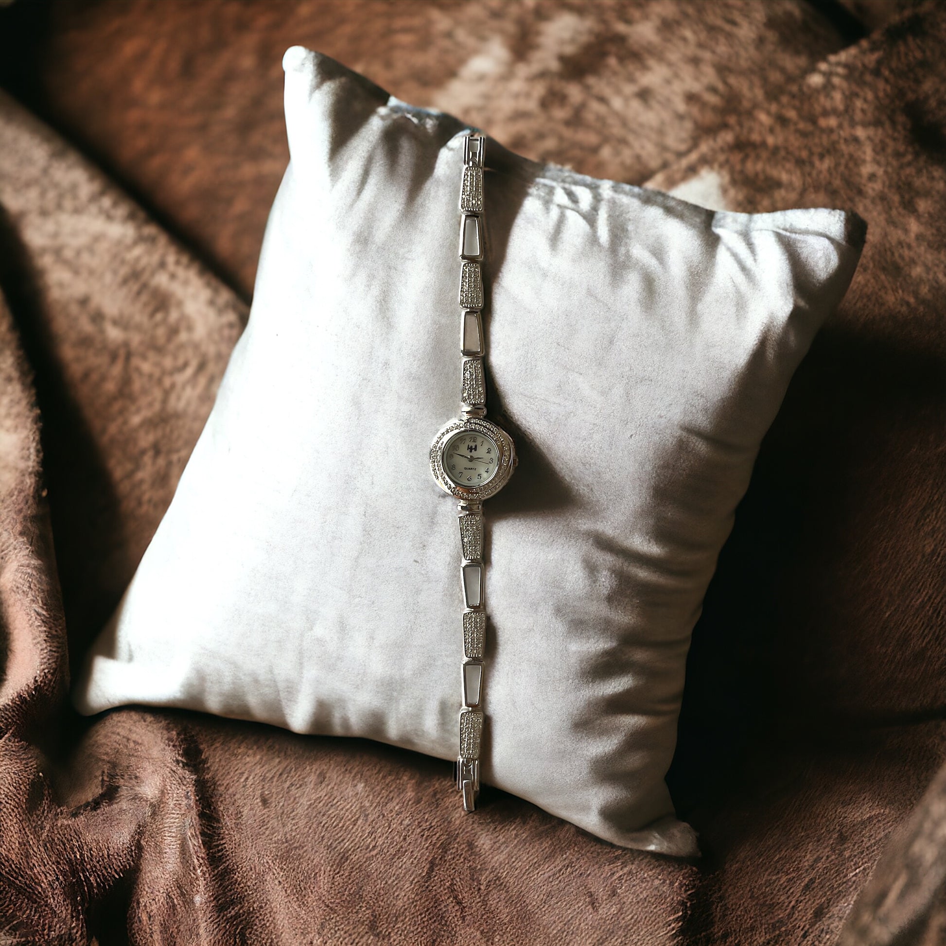 a watch sitting on a pillow on a bed