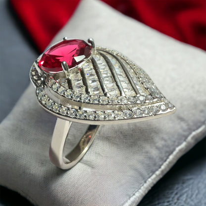 a ring with a large red stone surrounded by small white diamonds