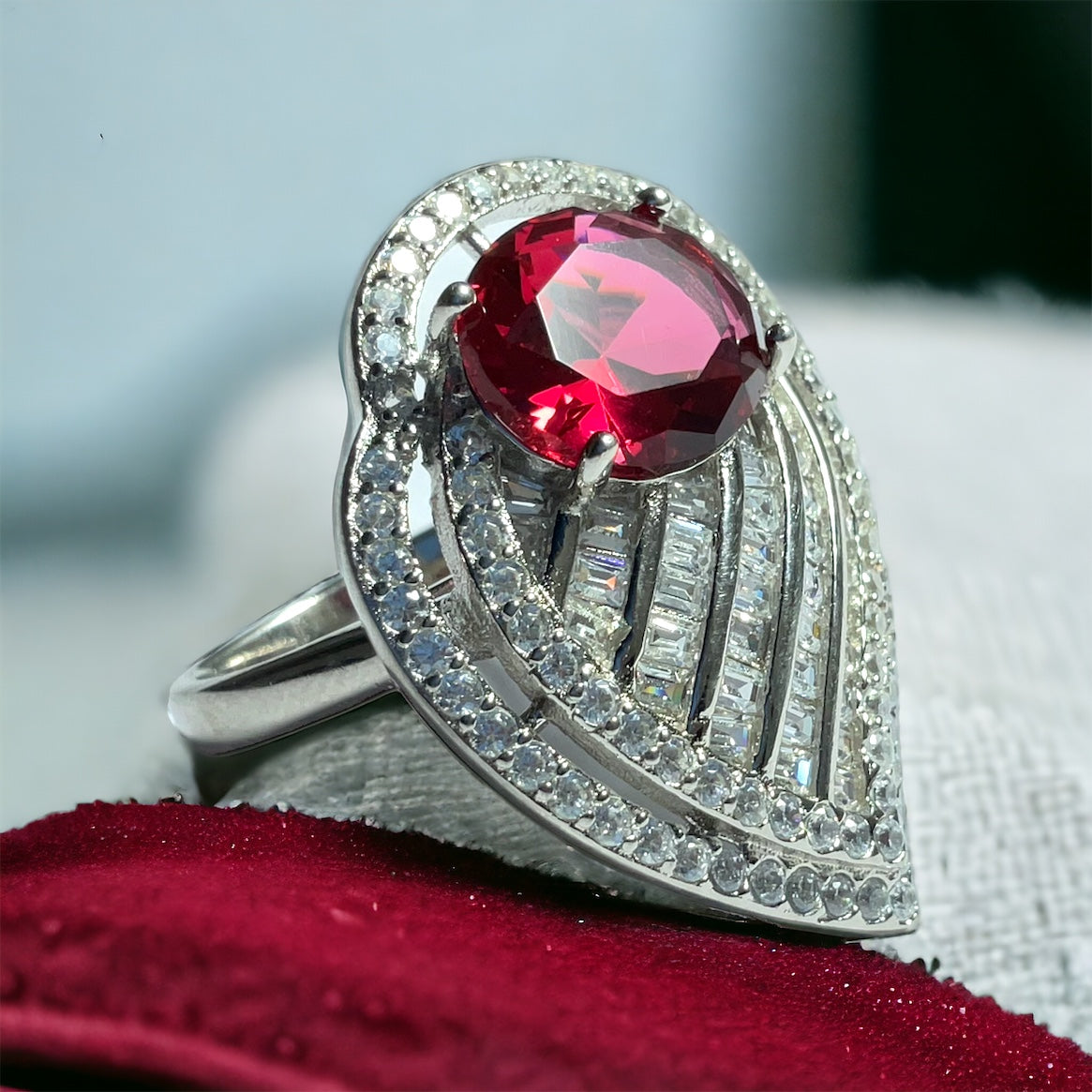 a ring with a large red stone surrounded by diamonds