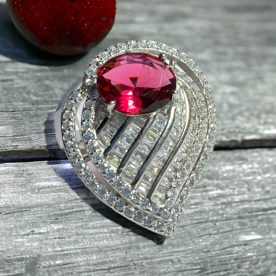 a red diamond ring sitting on top of a wooden table