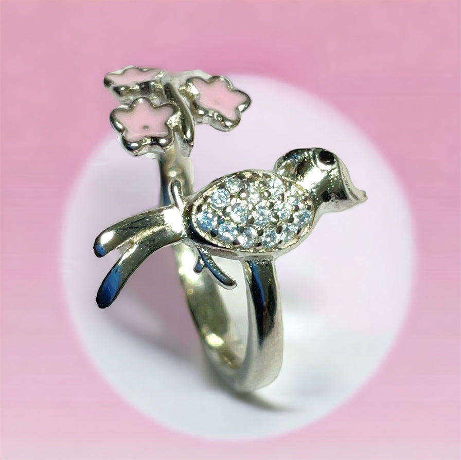 a silver ring with a bird and flowers on it